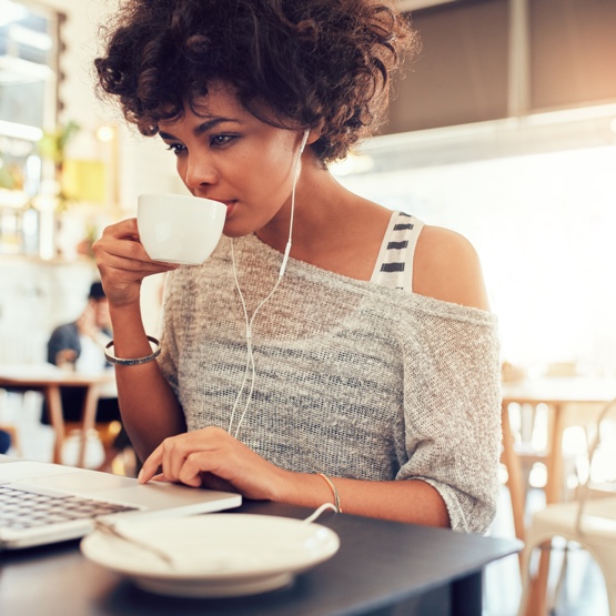 person drinking coffee whilst working on computer