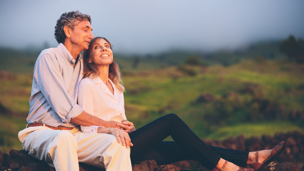couple sat together outdoors, smiling, embraced
