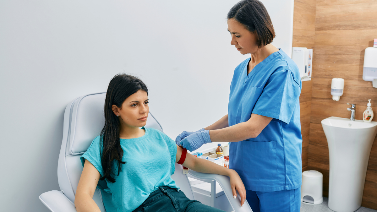 medical professional taking blood from patient sat on a chair