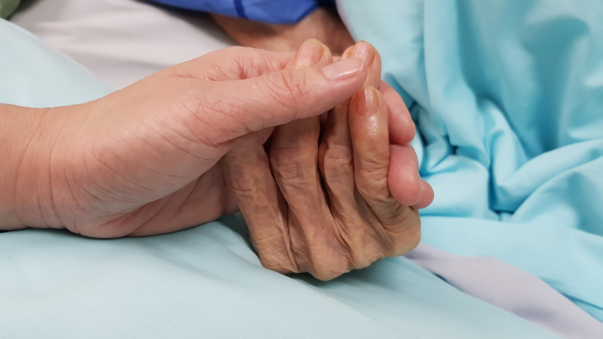 frail looking hand being held by another hand. suggesting end of life