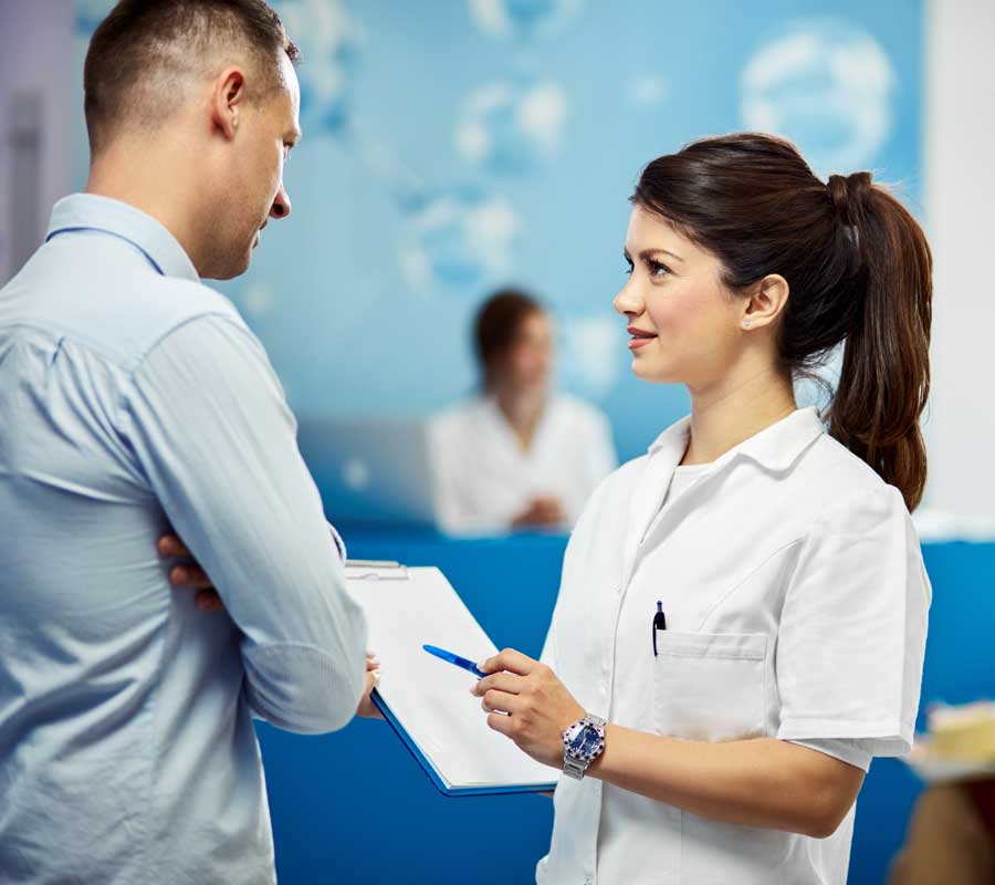 Nurse with clipboard talking to a man