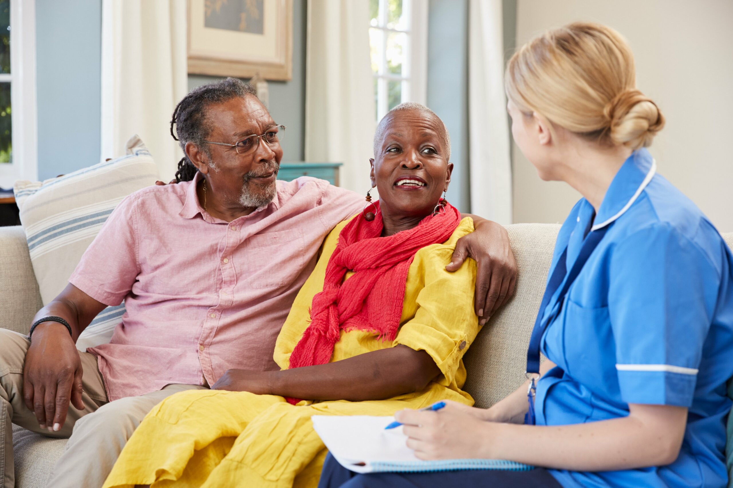 Nurse or healthcare worker talking to couple on sofa