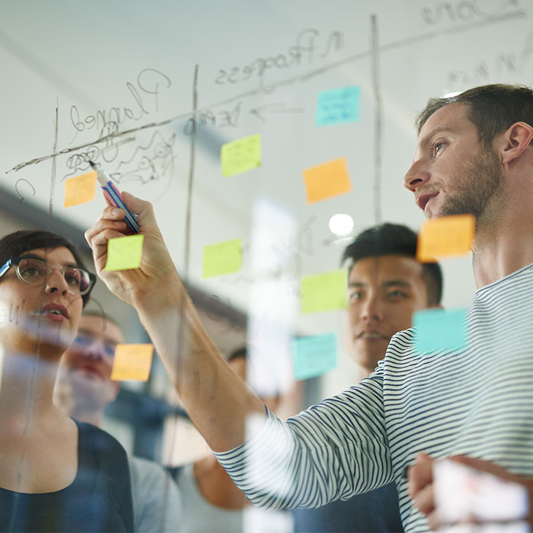 meeting of people, writing on a board, with post-it notes, brain storming ideas