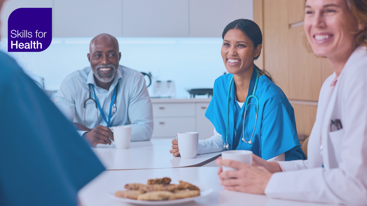 medical workers smiling in staff room with hot drinks and cookies on the table