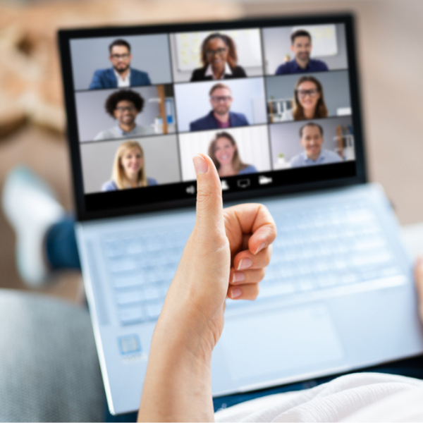 person giving thumbs up to a computer where a virtual meeting is taking place