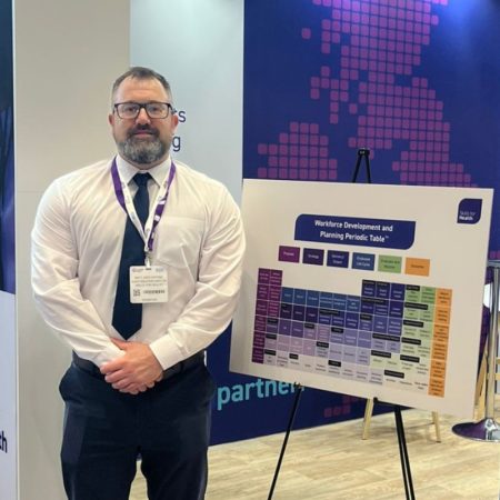 Matt Girdlestone stoof next to a printed version of the Workforce Planning Periodic Table