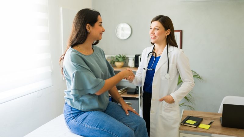 Female doctor happily shaking hands with her female patient after a successful consultation in her office