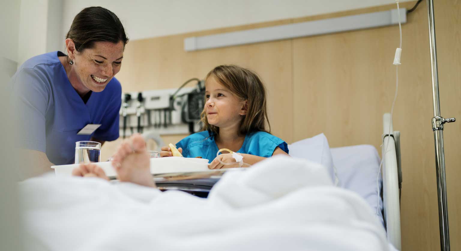 Photo of a child patient in bed with nurse to side