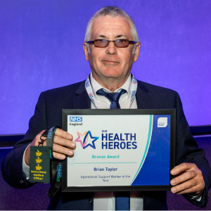 Photo of Brian Taylor holding his Our Health Heroes Awards certificate as a bronze winner