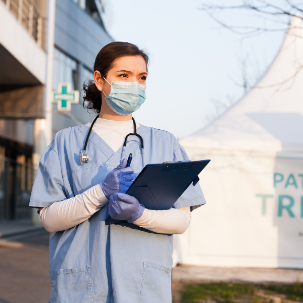 Female medical worker holding clipboard standing outside hospital