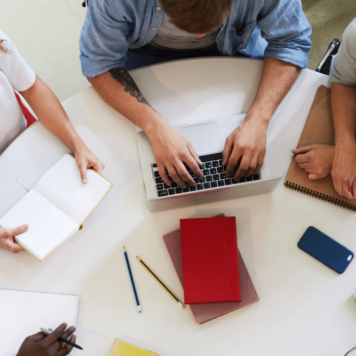 People sat around a table on computers and making notes