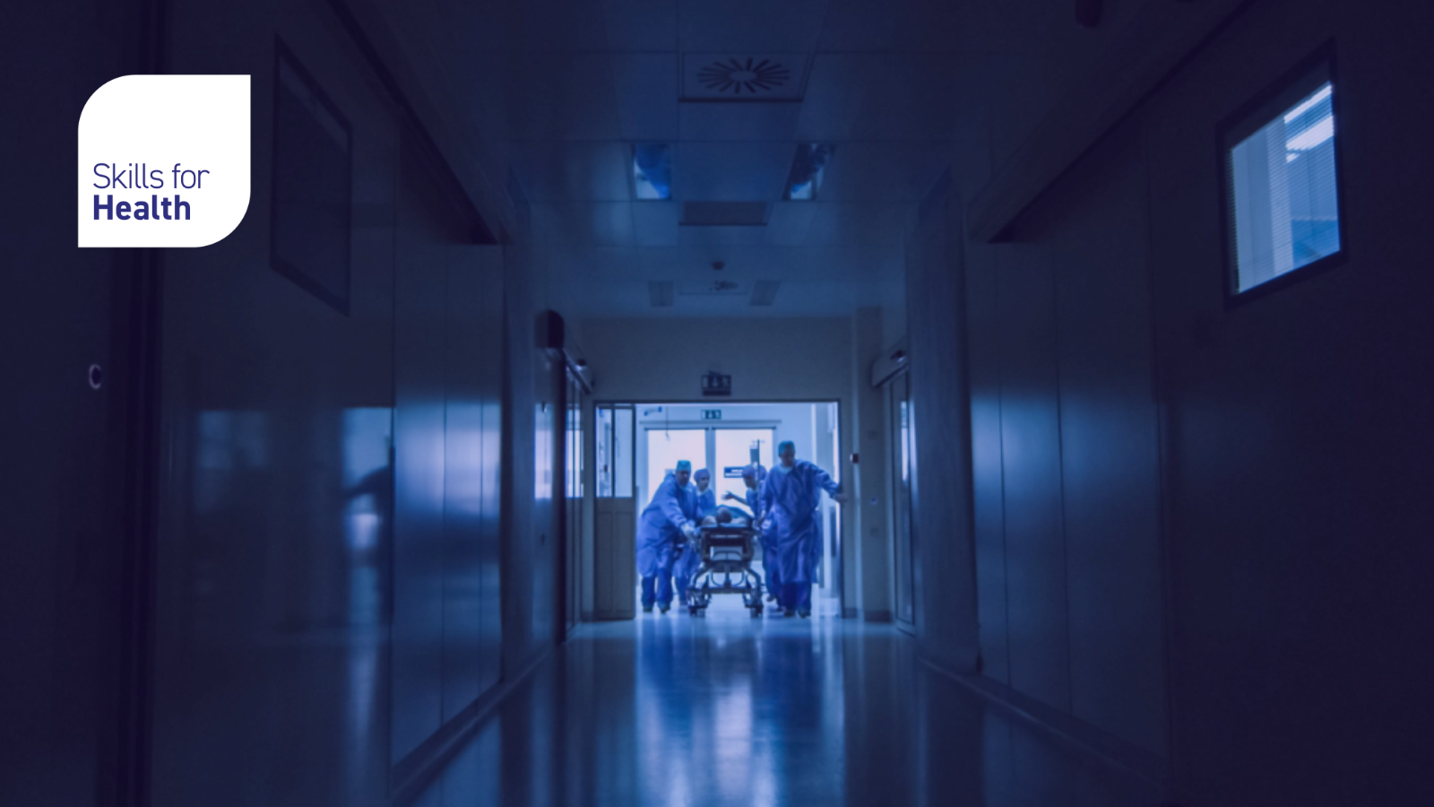 Hospital workers moving a patient in a dark corridor