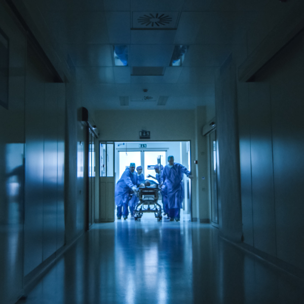 Hospital workers moving a patient in a dark corridor