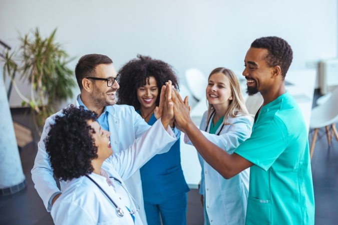 A close-knit group of healthcare professionals shares a joyful moment, showcasing teamwork and positivity in a clinical environment.
