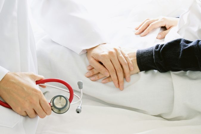 Medical doctor holding patient's hands and comforting her with care, Doctor supports her palliative patient with sympathy.
